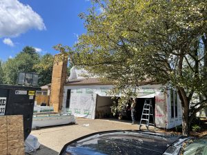 In-progress side view photo for a home that is removing old wooden siding and replacing it with James Hardie siding and trim